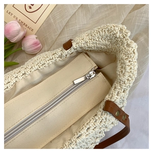 Detail of beige crochet tote bag with canvas lining, metal zipper and leather strap