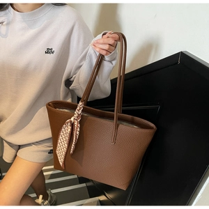 Detail of dark brown pebble leather tote bag with a checkered silk scarf on handle