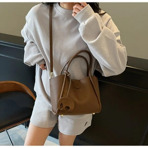 Detailaufnahme der braunen Eimertasche mit Litschi-Muster und niedlichem Elefantenanhänger