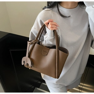 Nahaufnahme braune Handtasche aus Leder mit Elefantenanhänger und runden Griffen