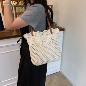 Handmade crochet tote bag with floral cutouts and brown leather handles for beach vacation