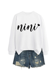 Close-up of white crewneck sweatshirt with black nini heart print and denim shorts