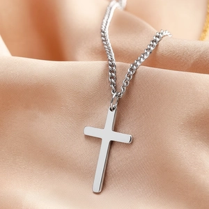 Minimalist stainless steel cross pendant necklace on champagne silk satin background