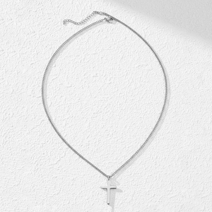 Minimalist silver stainless steel cross pendant necklace on a textured white background