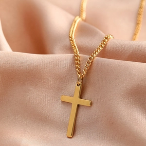 Macro shot of a polished gold cross pendant on a silk satin fabric background