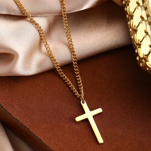 Macro shot of polished gold cross pendant necklace on champagne silk background