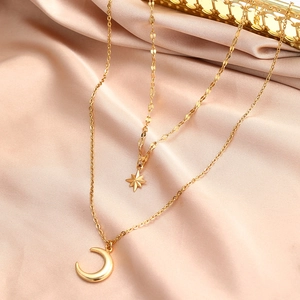 Detail of double-layer gold star and moon pendant necklace on pink satin fabric