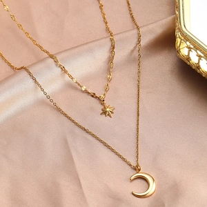 Detail of double-layer gold star and moon pendant necklace on elegant silk fabric