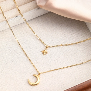 Detail of gold double-layer necklace featuring star and moon pendants on silk