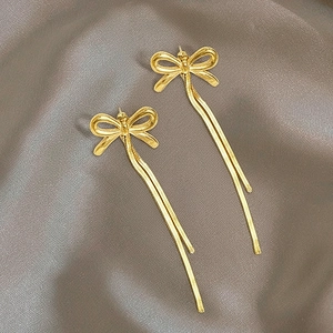 Détail de boucles d'oreilles nœud plaqué or 18K avec de longues chaînes serpentines
