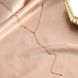 Collier minimaliste en Y en acier inoxydable doré sur fond de tissu satiné champagne