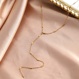 Vue détaillée du collier élégant en Y doré avec barres métalliques sur fond de soie