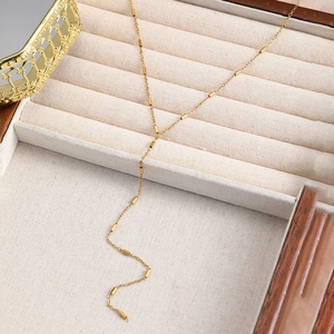 Détail d'un élégant collier en Y doré avec perles cylindriques dans un écrin en velours