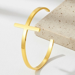 Detailed view of an 18K gold-plated stainless steel cross cuff bracelet on stone base