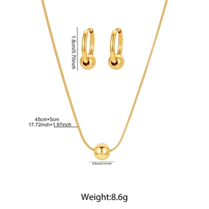 Détail d'un ensemble de bijoux en acier doré avec pendentifs perles et chaîne serpent