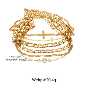 Détail de bracelets multicouches dorés en acier avec pendentif croix et cristal