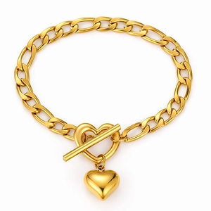 Detail of gold heart pendant and hollow heart toggle clasp on Figaro chain bracelet
