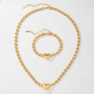 Close-up of golden heart pendant necklace and bracelet set with matte texture finish