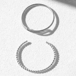 Detailed macro view of two silver stainless steel bracelets with cable and rope textures