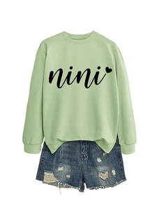 Detail of light green crewneck sweatshirt with nini heart print and ripped denim shorts