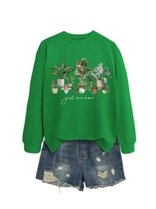 Flat lay of a green crewneck sweatshirt with potted plant graphics and denim shorts