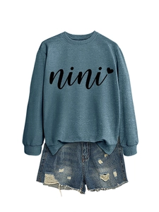 Detail showing nini heart print on casual blue crewneck sweatshirt with denim shorts