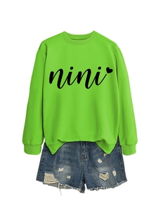 Detail view of neon green crewneck sweatshirt with nini heart print and denim shorts