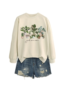 Flat lay of beige crewneck sweatshirt with botanical print and frayed denim shorts