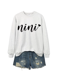 Detail of grey crewneck sweatshirt with nini heart print and distressed denim shorts
