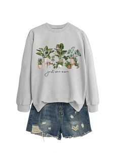 Flat lay of a grey sweatshirt with plant illustration and distressed denim shorts