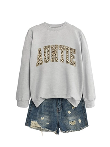 Détail du sweat gris avec texte AUNTIE imprimé léopard et short en jean vieilli