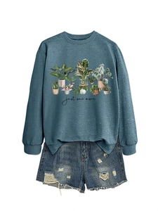 Detail of teal sweatshirt with botanical print paired with ripped denim shorts