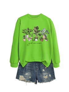 Flat lay of a vibrant green sweatshirt with botanical prints and denim shorts for women