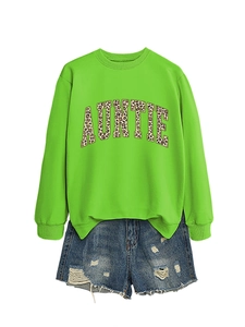 Détail du sweat vert Auntie avec lettres léopard et short en jean bleu à trous