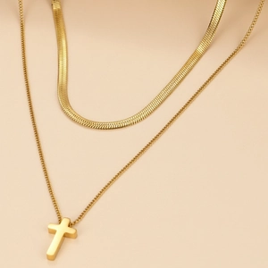 Macro view of double-layered gold flat snake chain with a solid cross pendant necklace