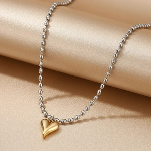 Two-tone heart pendant necklace with gold heart charm and silver bead chain on satin