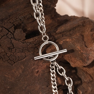 Macro shot of silver OT clasp and chunky layered chain links against a wood background