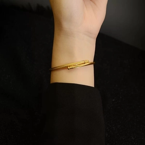 Minimalist gold stainless steel cable twist open cuff bracelet worn on a wrist