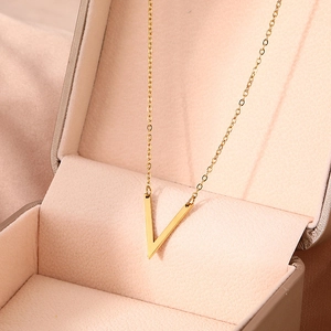 Vue détaillée d'un collier pendentif V doré sur un coffret à bijoux en soie rose