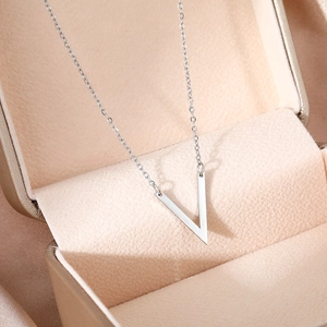 Détail du collier avec pendentif en V argenté présenté dans un écrin cadeau de luxe champagne