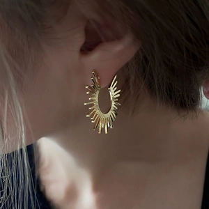 Golden sunburst semicircle hoop earrings in minimalist style shown on model