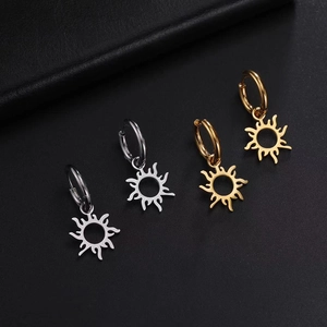 Minimalist sun pendant hoop earrings in gold and silver finishes on dark leather background