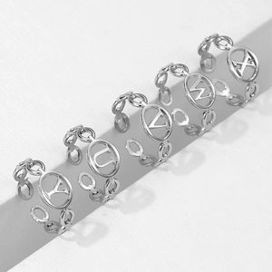 Close-up of silver chain rings featuring T, U, V, W, X letter charms on white platforms