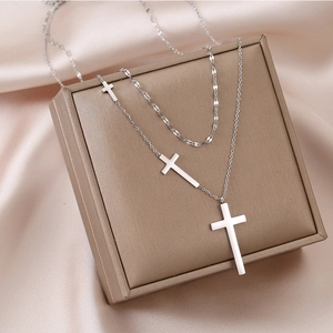 Collier double couche en acier inoxydable avec croix sur un écrin de bijoux champagne