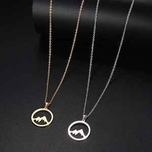 Détail des colliers avec pendentif montagne en or et argent sur un support minimaliste