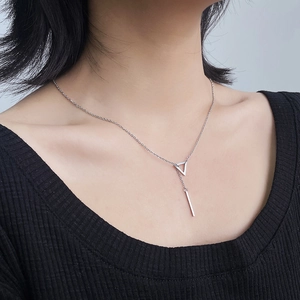 Detail of silver stainless steel geometric triangle and vertical bar pendant on collarbone