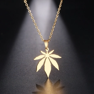 Detailed view of a gold-plated maple leaf necklace with an O-chain on a dark background
