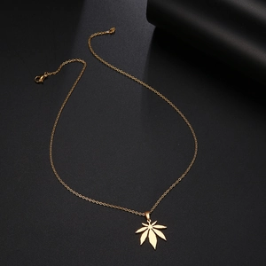 Detailed view of a golden maple leaf pendant necklace with a lobster clasp on black background