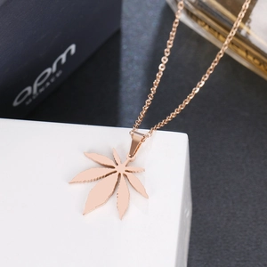 Detail of rose gold maple leaf pendant necklace on white marble block display
