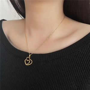 Close-up of interlocking gold heart pendants on a necklace worn by a female model